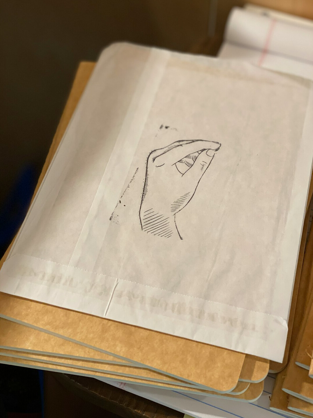 Close study of a hand resting on a stack of handwritten research notes