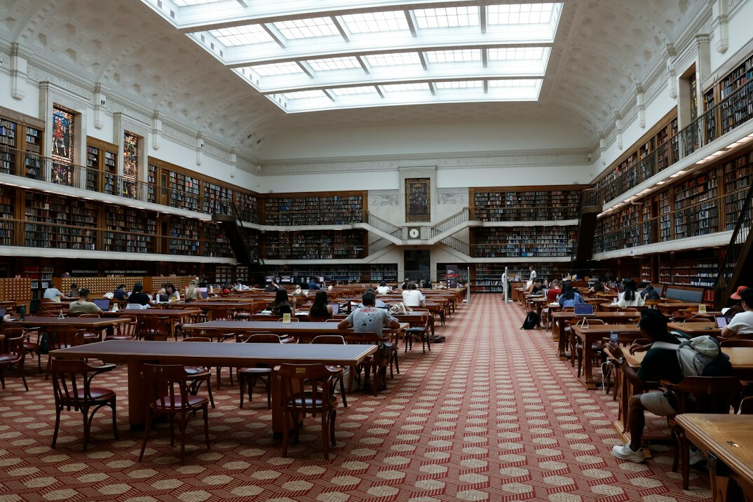 Empty museum-like reading room with long tables and soft daylight
